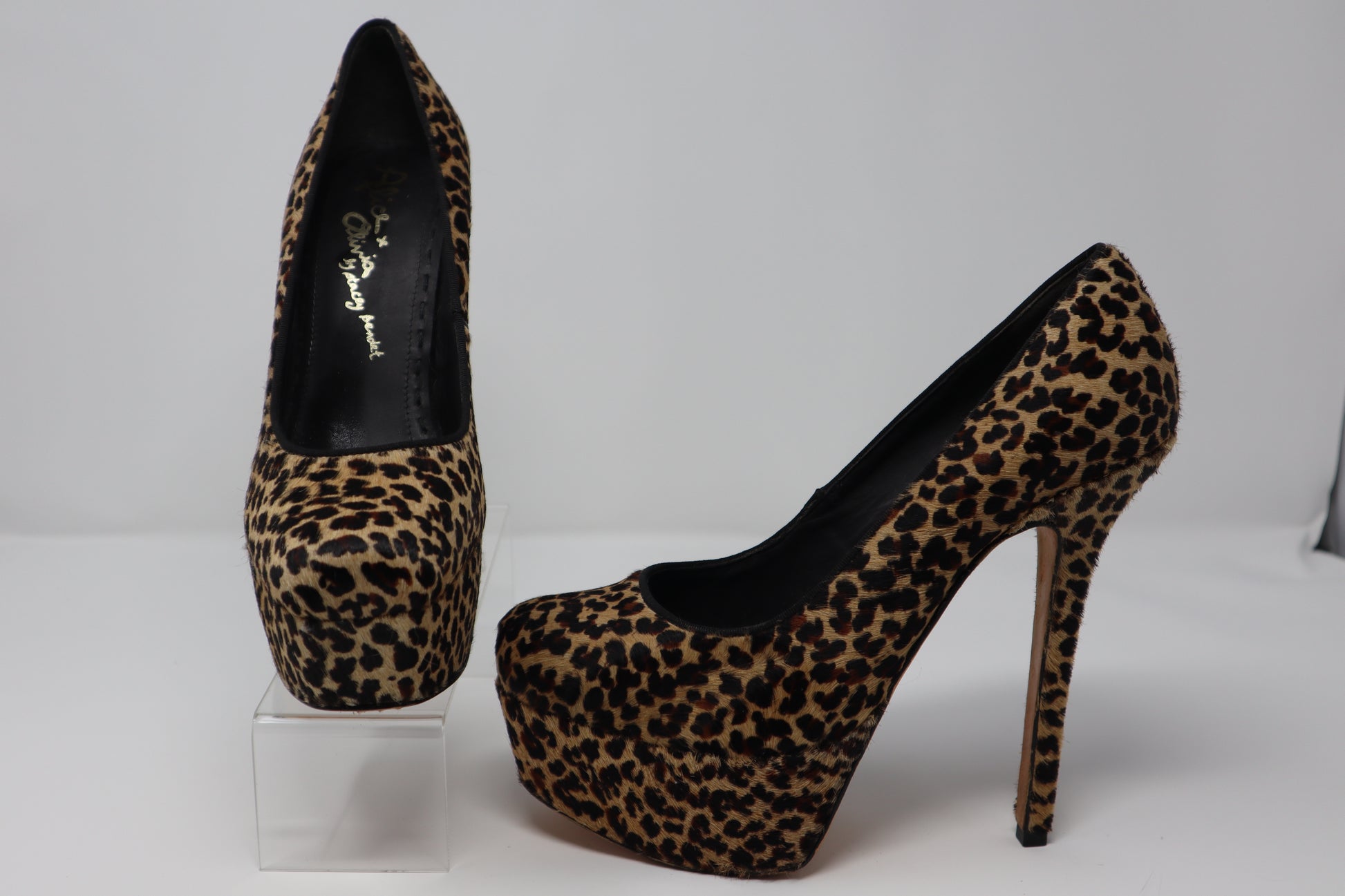 A bold pair of Alice + Olivia by Stacey Bendet platform pumps featuring luxurious pony hair with a striking leopard print. These shoes have a stiletto heel and a platform base, combining both height and comfort, perfect for making a statement with any outfit.