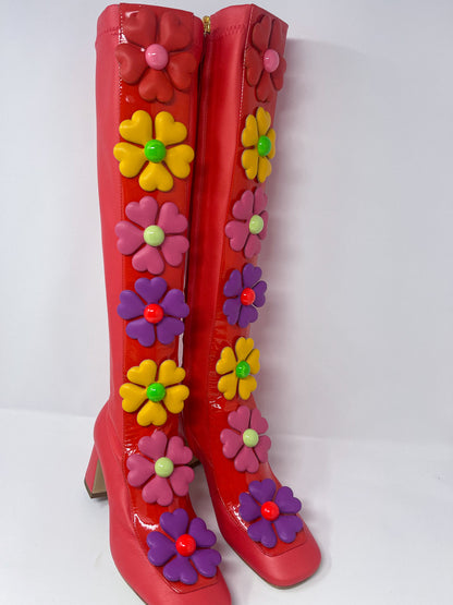 Red stretch fabric boots by Moschino, adorned with vibrant, oversized flowers featuring heart-shaped petals along a glossy patent leather band.