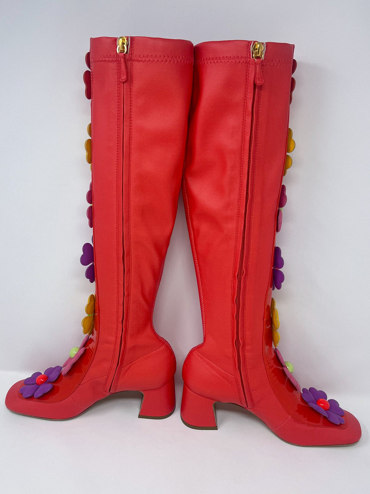 Red stretch fabric boots by Moschino, adorned with vibrant, oversized flowers featuring heart-shaped petals along a glossy patent leather band.