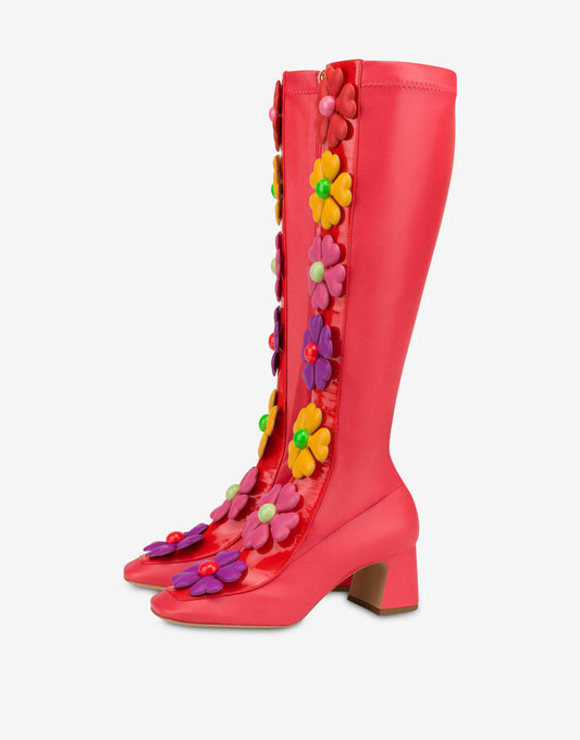 Red stretch fabric boots by Moschino, adorned with vibrant, oversized flowers featuring heart-shaped petals along a glossy patent leather band.